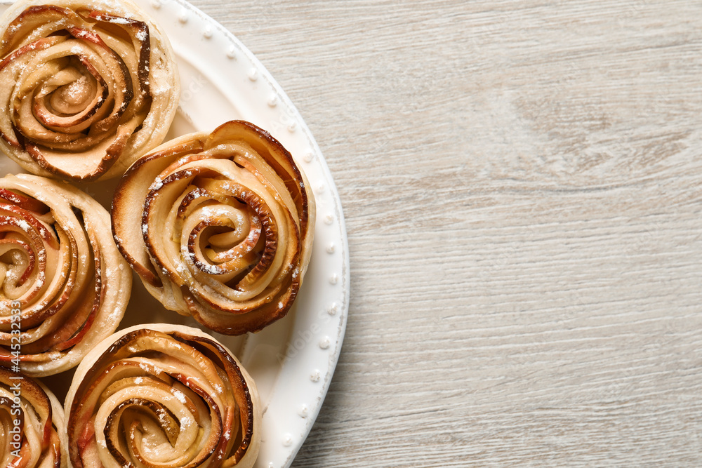 Fototapeta premium Freshly baked apple roses on white wooden table, top view. Space for text