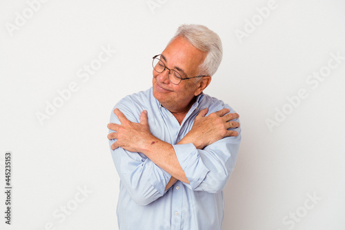 Senior american man isolated on white background hugs, smiling carefree and happy.
