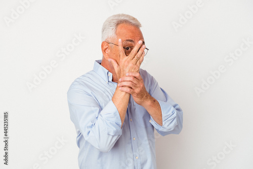 Senior american man isolated on white background blink through fingers frightened and nervous.