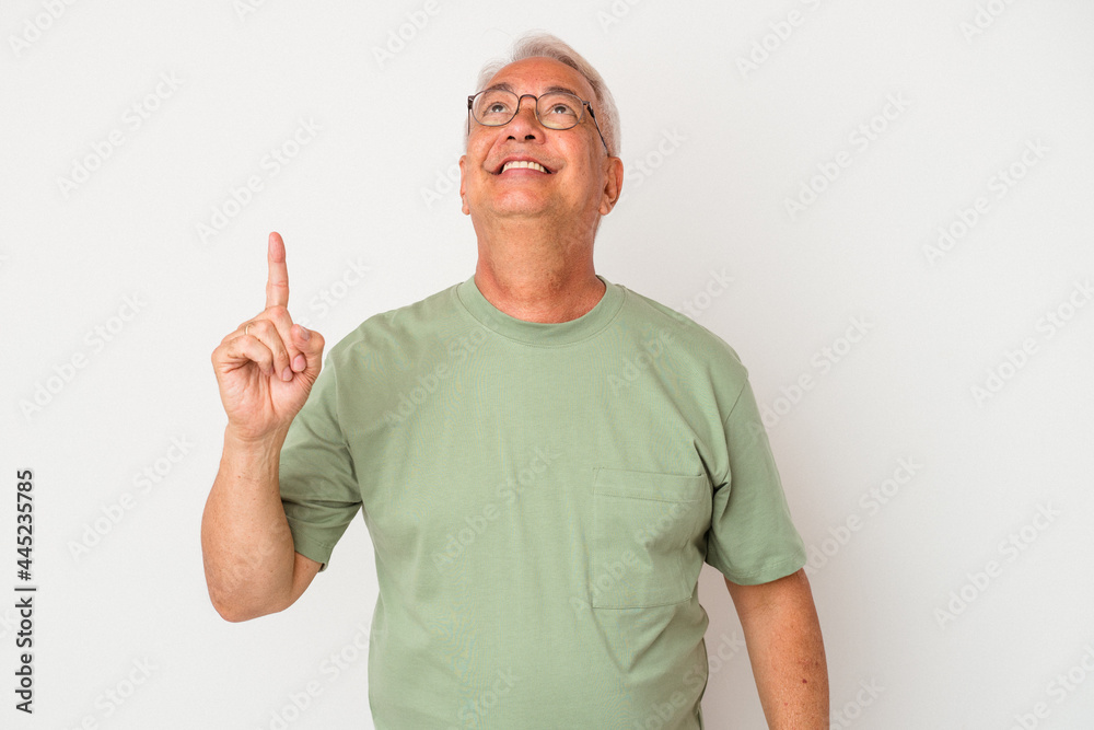 Senior american man isolated on white background indicates with both fore fingers up showing a blank space.
