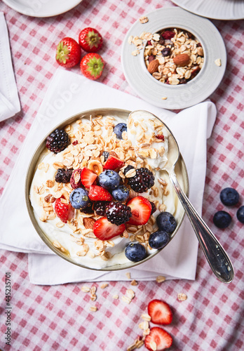 yogurt with berries and granola ON A RED SQUATE TABLECLOTH
