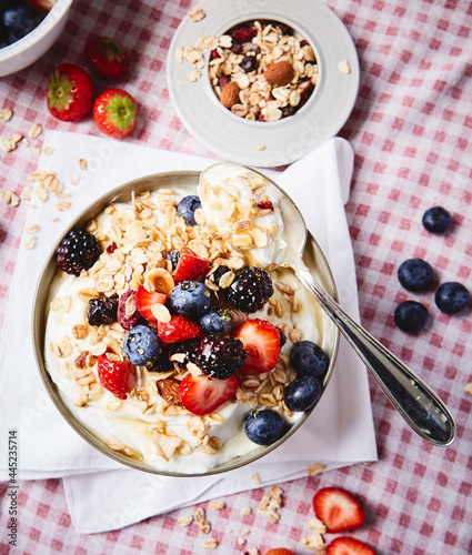 yogurt with berries and granola ON A RED SQUATE TABLECLOTH
