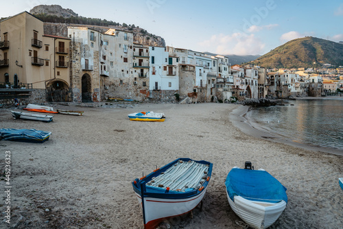 Beautiful old harbor with wooden fishing boats,colorful waterfront stone houses and sandy beach in Cefalu, Sicily, Italy.Attractive summer cityscape,traveling concept background.Italian vacation.