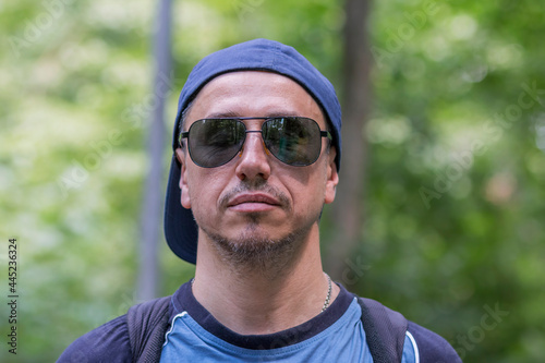 guy with closed eyes, in glasses with a backpack on his shoulders, in the woods, close-up