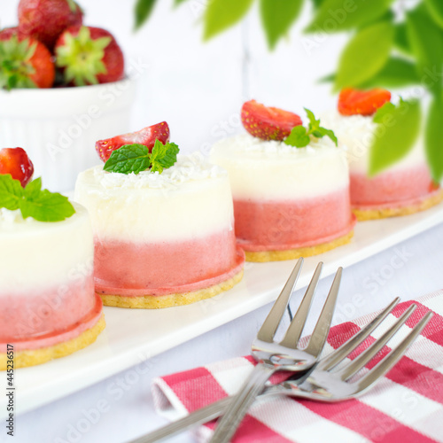 Mini coconut and strawberry cheesecakes. Monoportions of summer dessert with coconut, white chocolate and fresh strawberries.
