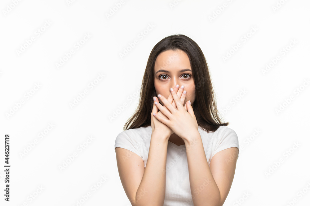 Young woman holding hands over her mouth against a white background. Young woman holding hands over her mouth against a white background.