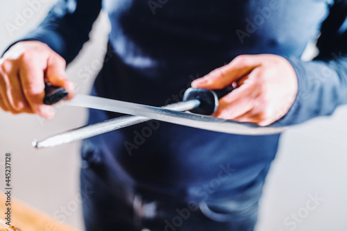 Anonymous person sharpening ham knife before cutting ham. Very well sharpened quality knife.