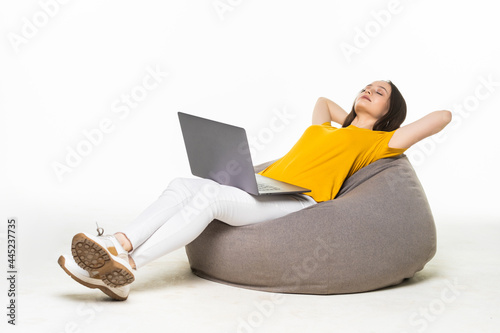 Profile side view of girl sitting in bag chair using laptop making project start-up isolated over lwhite color background photo