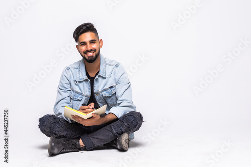 Man sitting on the floor studying over a white background