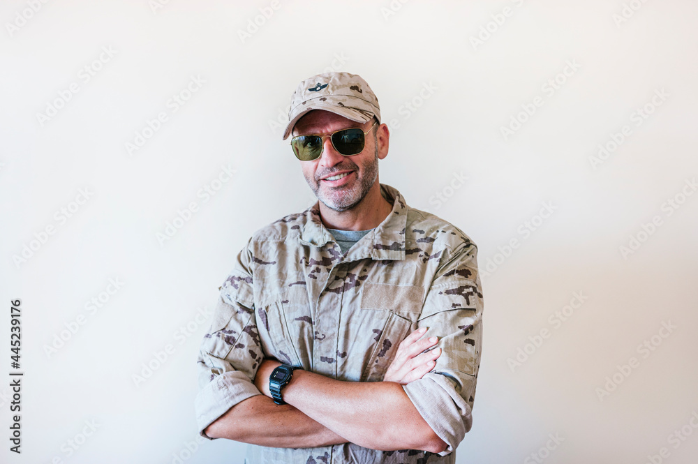 Caucasian man in camouflaged army uniform crossing arms