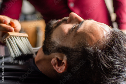 Barber brushing customer's beard in a barbershop
