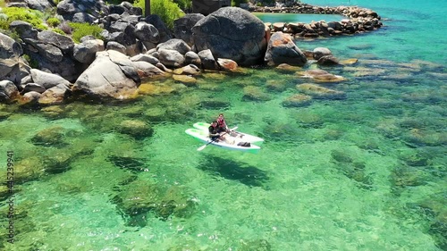 Aerial view of a couple kayaking on Lake Tahoe in California. The water is turquoise and mountains can be seen in the background with blue skies.