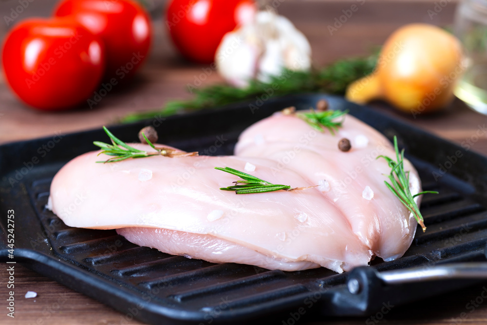 raw chicken fillet with garlic, pepper and rosemary on a wooden background raw chicken fillet with garlic, pepper and rosemary on a wooden background