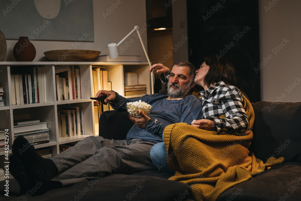 couple relaxing at home watching tv while sitting on a sofa. couple relaxing at home watching tv while sitting on a sofa.