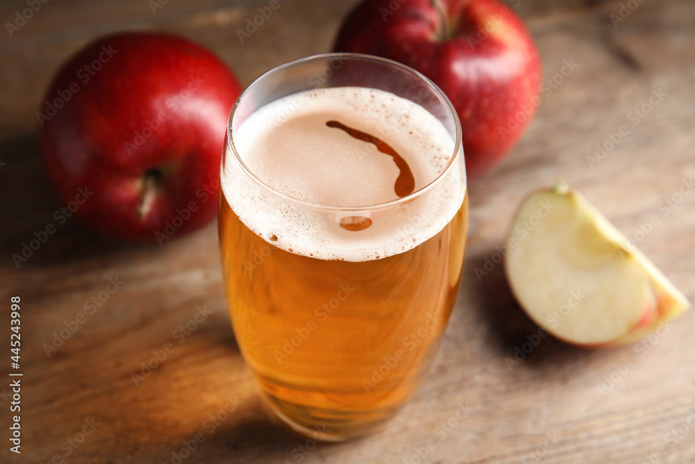 Glass of delicious cider and ripe red apples on wooden table, closeup Glass of delicious cider and ripe red apples on wooden table, closeup