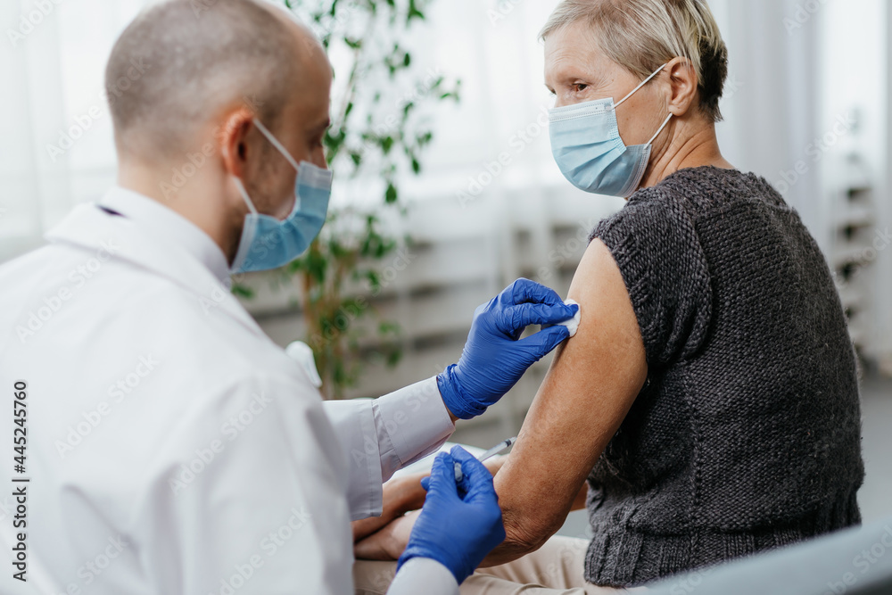 Fototapeta premium woman in a protective mask is vaccinated in a medical office.