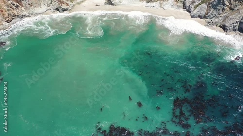 Aerial view of the California coastline near Big Sur State Park. Cliff edges can be seen as well as turquoise ocean waves with algae. photo