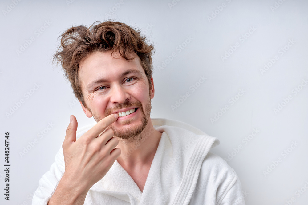 Close-up of bearded young man looking at camera checking is mouth and teeth in bathroom, checking their health state. Handsome guy in the morning after taking bath, Prthodontics, people lifestyle Close-up of bearded young man looking at camera checking is mouth and teeth in bathroom, checking their health state. Handsome guy in the morning after taking bath, Prthodontics, people lifestyle