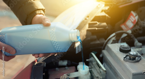 Man filling car radiator with antifreeze outdoors, closeup photo