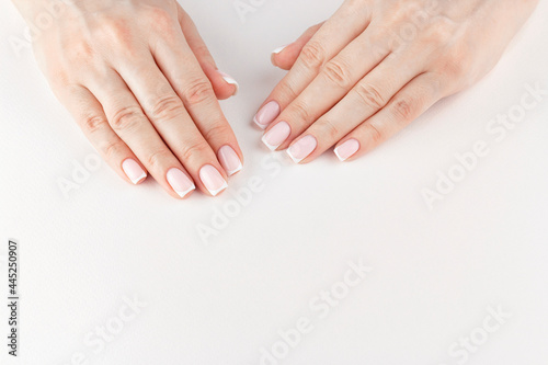 Female hands with beautiful stylish french manicure above white background with copy space