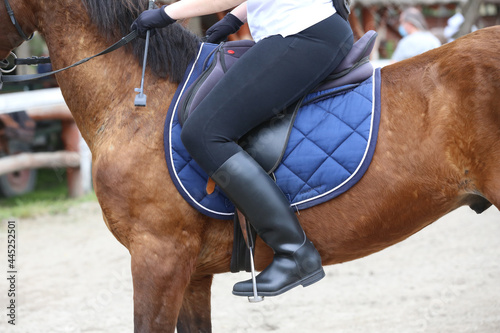 Old leather saddle with stirrups for show jumping race. Equestrian sport event background
