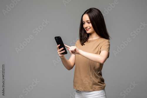 Young attractive european student scrolling news feed in her smartphone with concentrated expression, isolated over white background. Girl watches live stream through some app