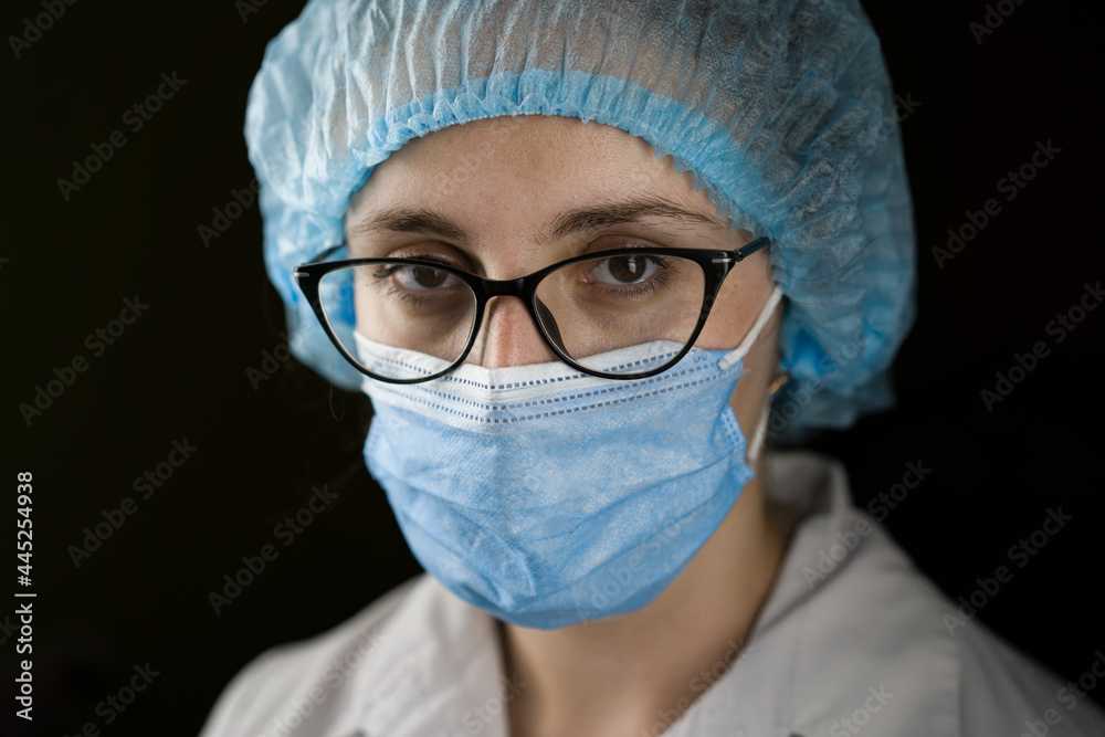 Portrait of a young female doctor in a white coat and mask. Smiling at the camera Portrait of a young female doctor in a white coat and mask. Smiling at the camera