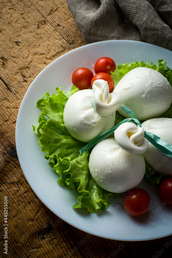 plate with mozzarella campana and cherry tomatoes, over wooden table. detail plate with mozzarella campana and cherry tomatoes, over wooden table. detail