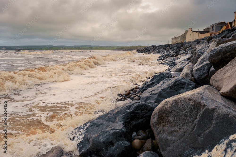 Wet rocks of Atlantic coast at Lahinch town, county Clare, Ireland. Low cloudy sky, rough storm weather.
