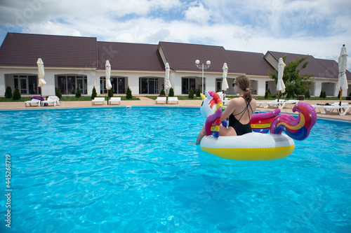 Happy woman on unicorn pool float in pool. Summer holidays