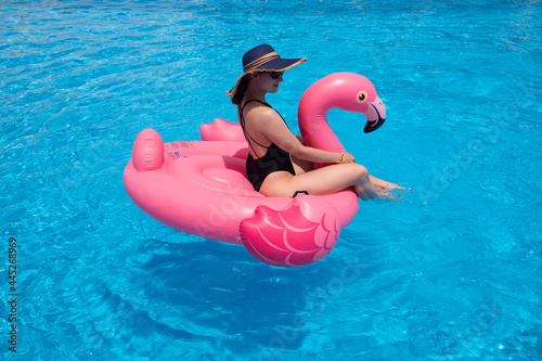 Woman on flamingo pool float in pool. Summer holidays, enjoying summer vacations during quarantine. © Marharyta