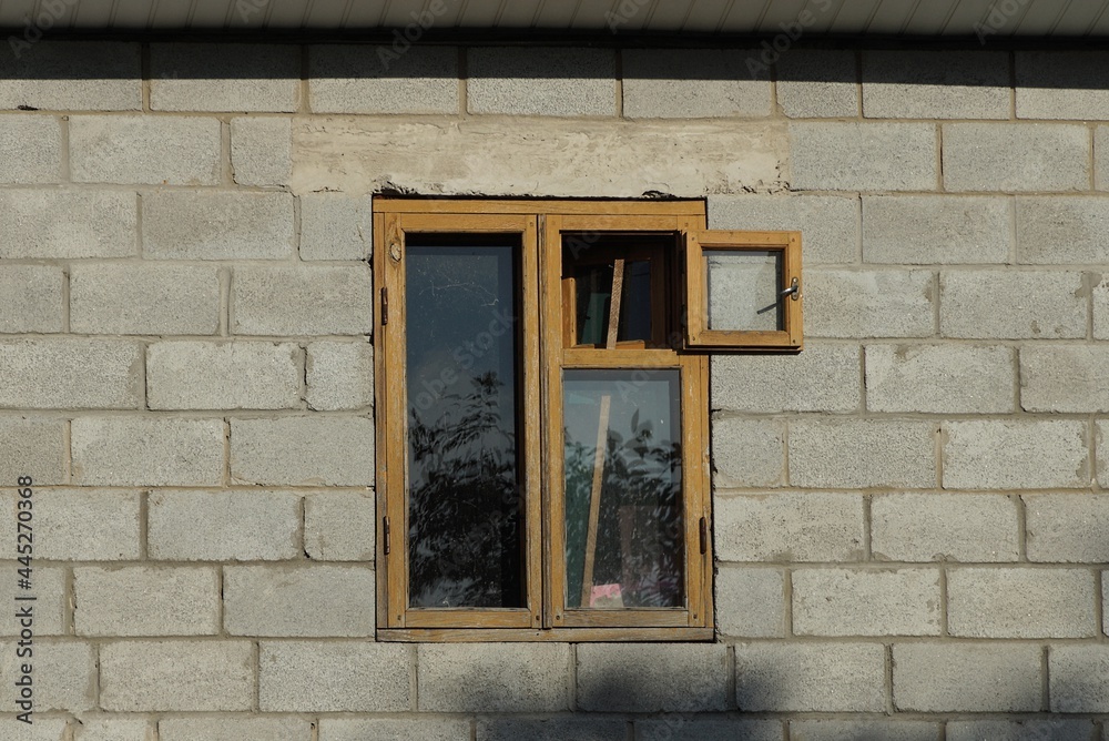 Obraz premium one brown old wooden window on a gray brick wall of a building