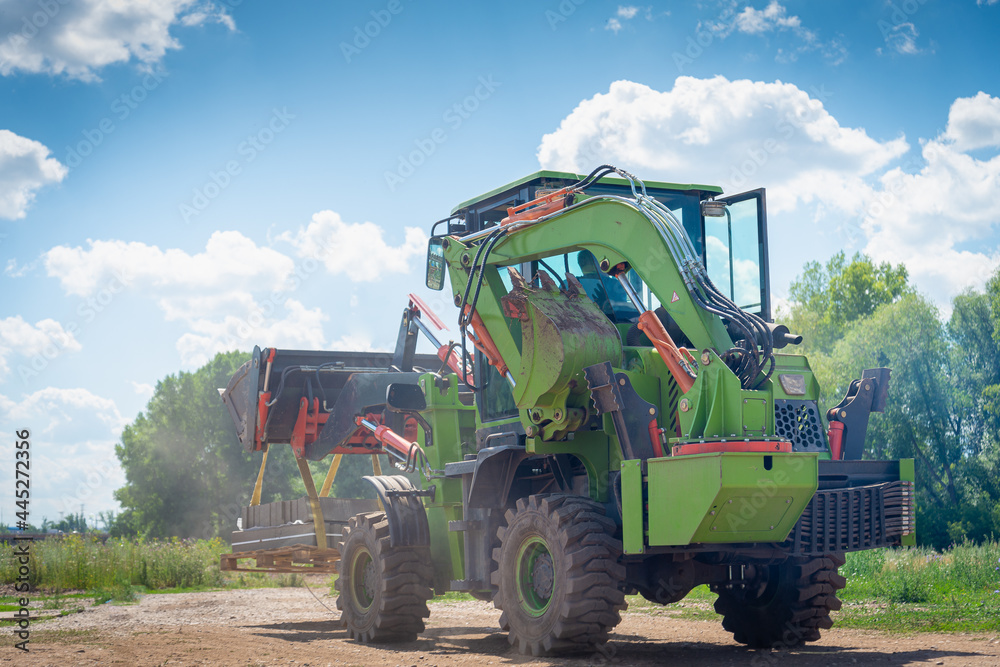 Fototapeta premium Construction equipment (tractor with a bucket) works in the park.