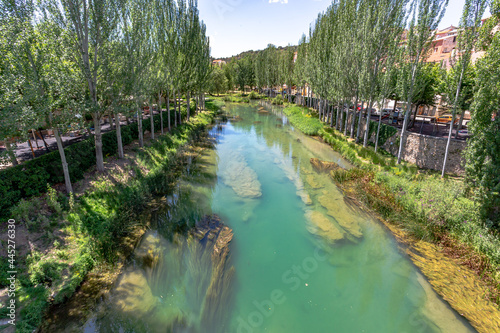 Rio Tajo as it passes through the town of Trillo in Guadalajara. Rio Grande. Urban landscape. Lush trees on the banks of the river Tagus. Medieval bridge over the river Tagus