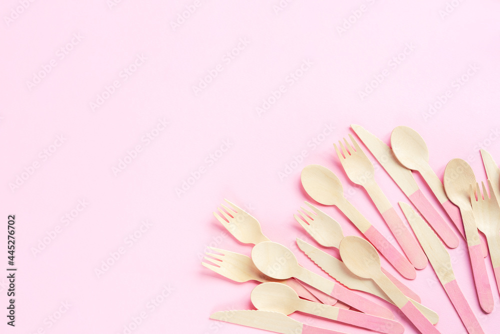 Disposable bamboo spoons, forks and knives on pink background. Zero waste concept. Top view, flat lay, copy space