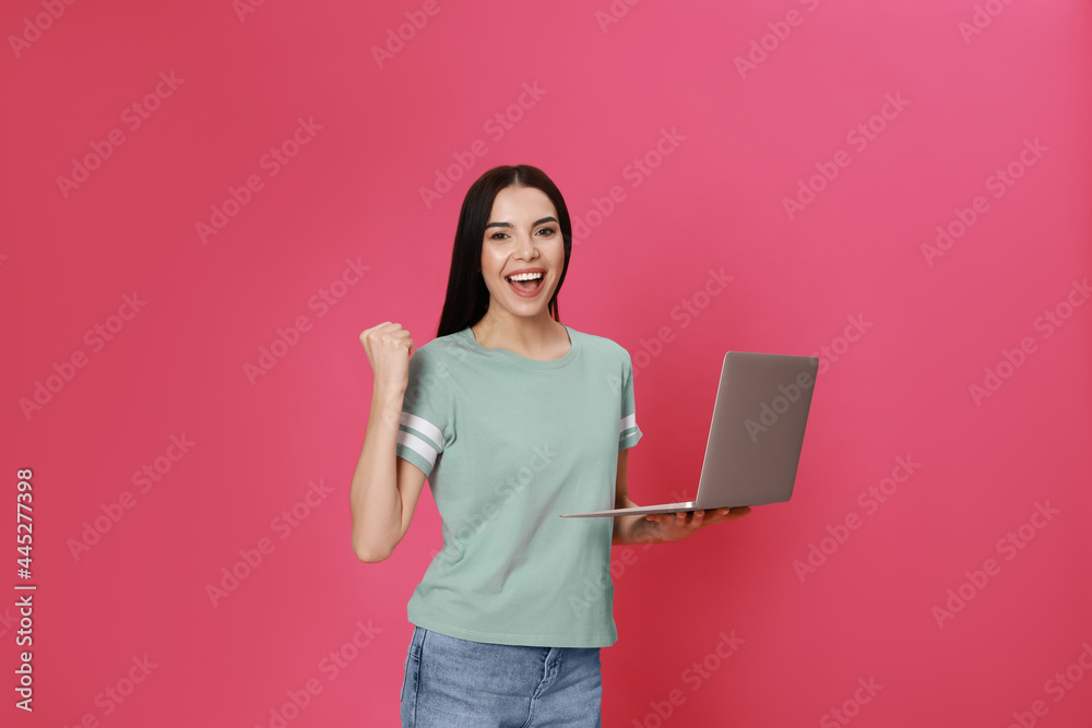 Emotional young woman with modern laptop on pink background Emotional young woman with modern laptop on pink background