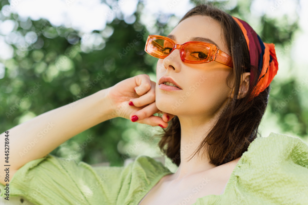 Low angle view of woman in sunglasses looking at camera outdoors Low angle view of woman in sunglasses looking at camera outdoors