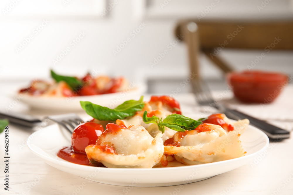 Tasty ravioli with tomato sauce served on white table