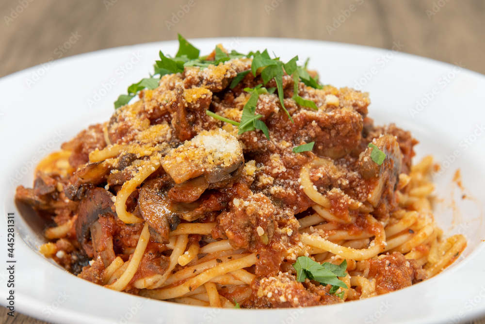 Large bowl of fettuccini bolognese pasta covered in sauce, mushroom, and garnishment for a hearty meal