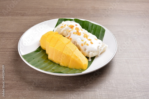 Thai fresh mango fruit with glutinous sticky rice in sweet coconut cream sauce on wood background asian dessert menu