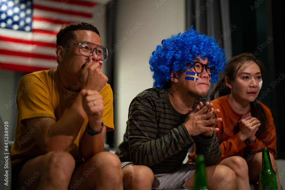 Group of Asian people friends sit on sofa watching and cheering sports games competition on TV together at home. Excited man and woman sport fans celebrate sport team victory in national sports match Group of Asian people friends sit on sofa watching and cheering sports games competition on TV together at home. Excited man and woman sport fans celebrate sport team victory in national sports match