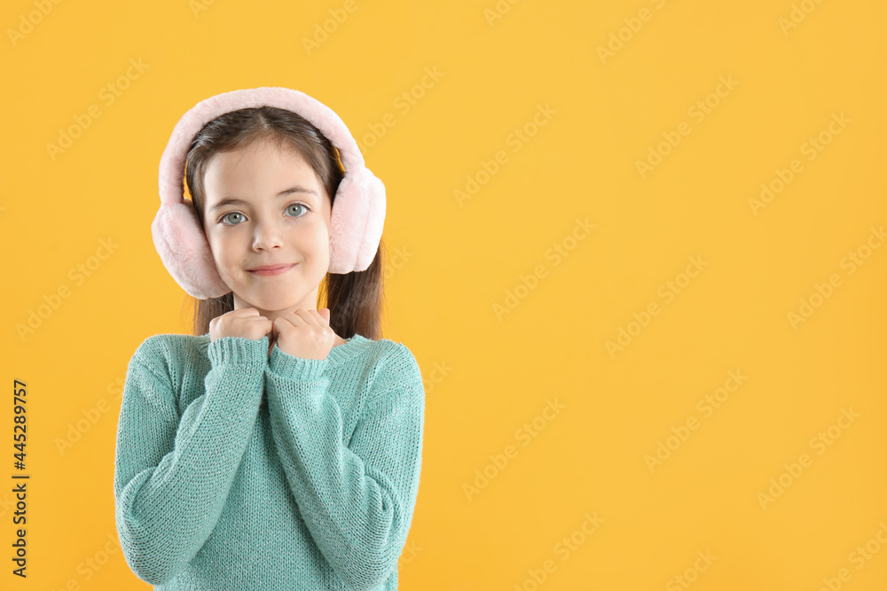 Cute girl wearing stylish earmuffs on yellow background. Space for text Cute girl wearing stylish earmuffs on yellow background. Space for text
