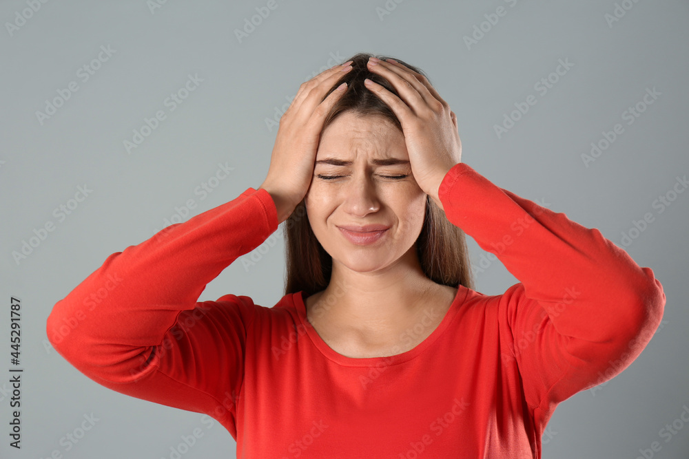 Young woman suffering from migraine on grey background Young woman suffering from migraine on grey background