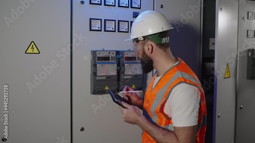 worker is checking electric panel and filling meter reading in electronic report