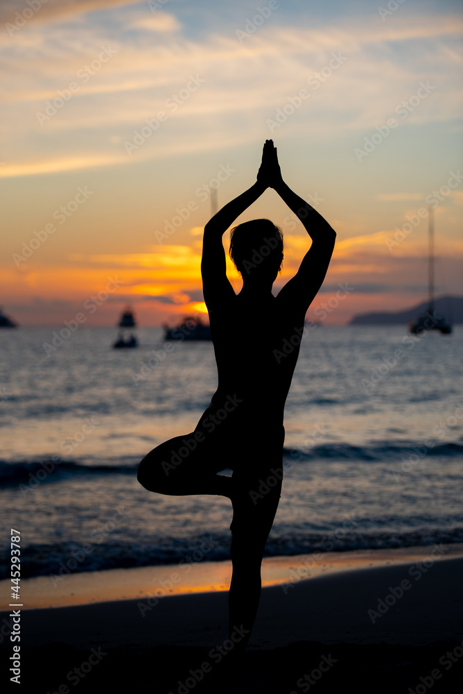 Silhouette of Fitness model doing yoga at sunset time.