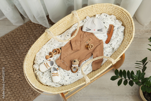 Photography Cute baby clothes and accessories in basket bassinet at home, top view