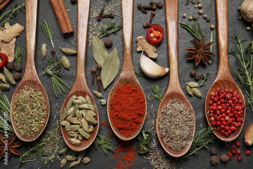 Flat lay composition with different natural spices and herbs on black table