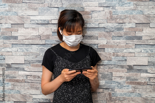 マスクをしてスマートフォンを使う若い女性