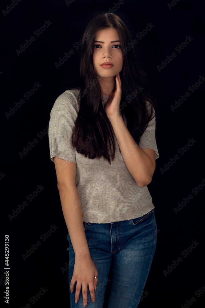 Fashion photo of a beautiful model with long hair, wearing grey top,  fashion pose, studio portrait, dark background.