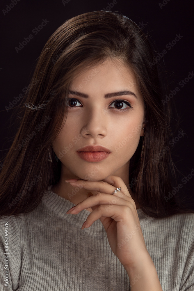 Fashion photo of a beautiful model with long hair, wearing grey top, fashion pose, studio portrait, dark background, close up pic. Fashion photo of a beautiful model with long hair, wearing grey top, fashion pose, studio portrait, dark background, close up pic.